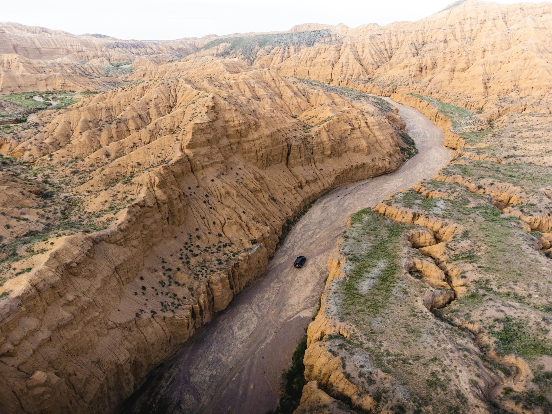 Car driving on a dry riverbed in a canyon