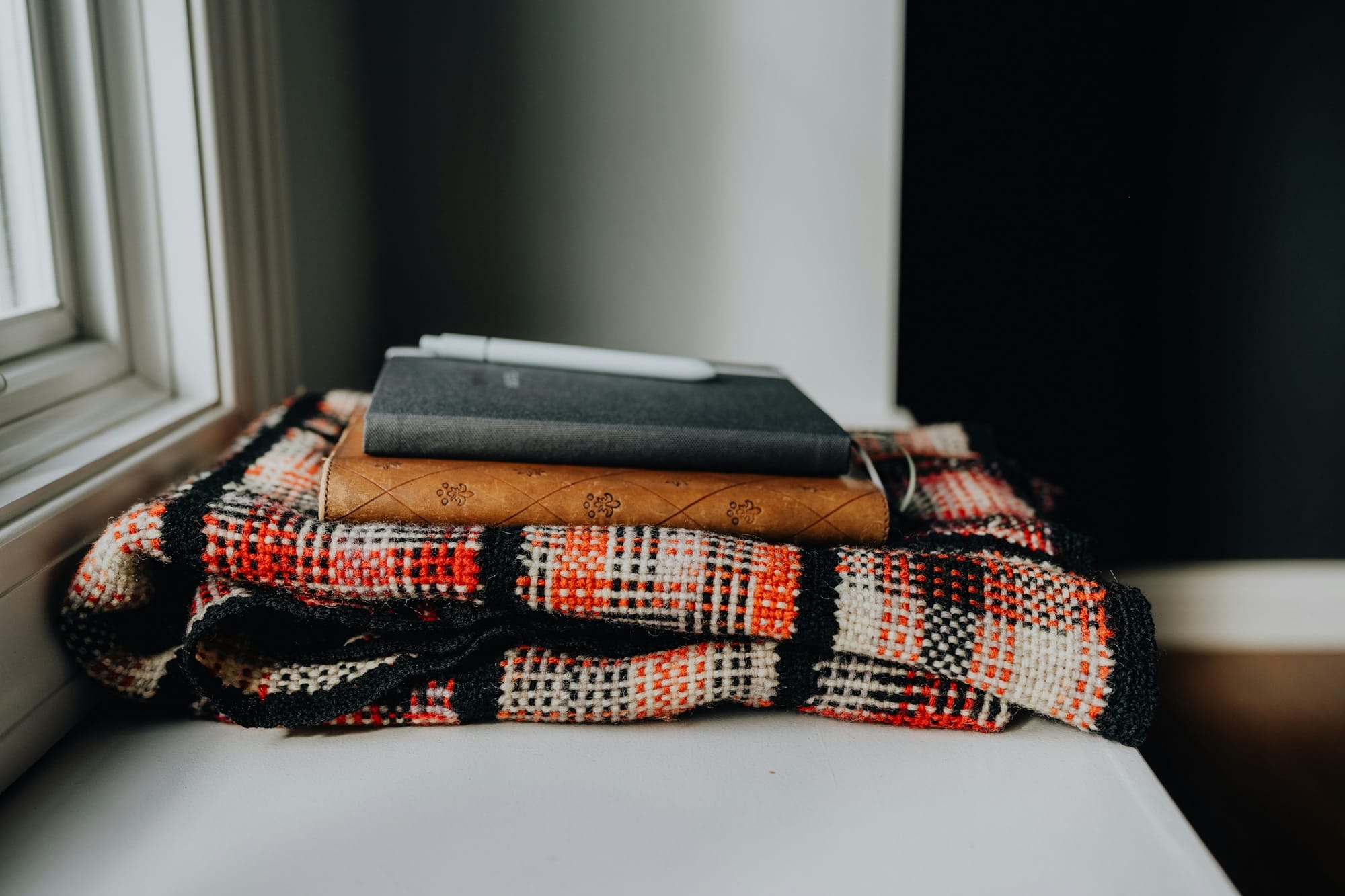 A stack of books on a blanket on a window sill