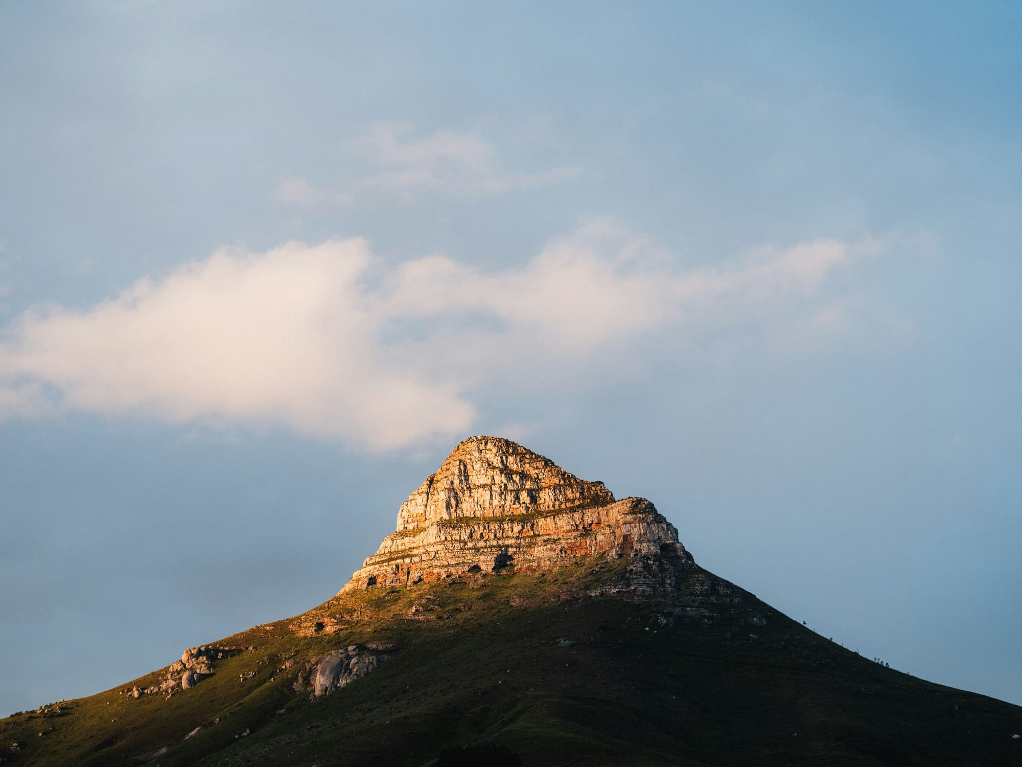 A rocky mountain face under a shadow with clouds behind it