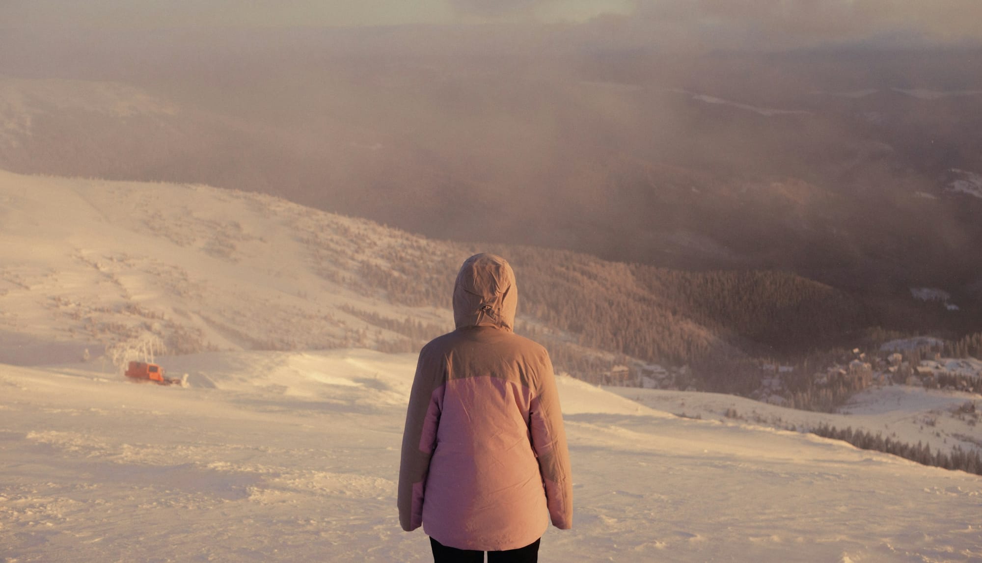 A person in a snow coat on a snowy mountain looking out